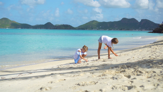 两个孩子在热带沙滩上造沙城堡和玩耍视频