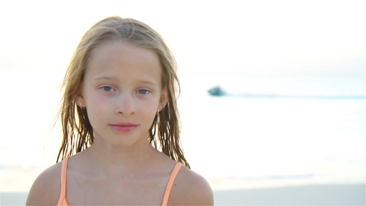 小女孩的肖像看着镜头和微笑的背景天和海的相片视频