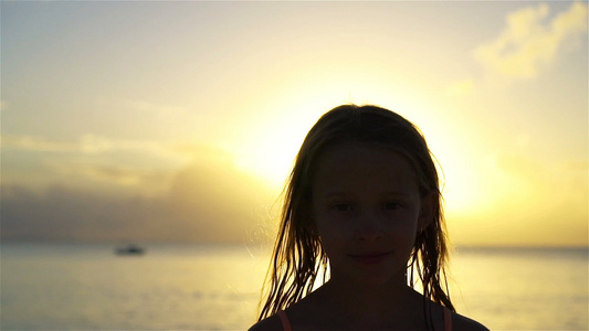 小女孩的肖像看着镜头和微笑的背景美丽的天空和海洋笑声视频