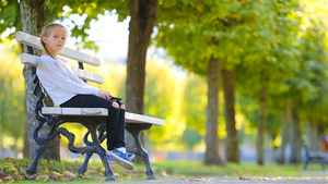 美丽的秋天女孩坐在公园凳子上10秒视频
