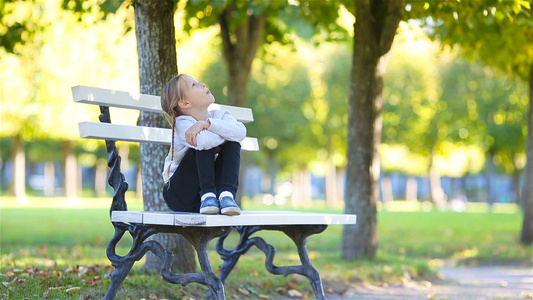 可爱的小女孩在户外美丽的秋日可爱的孩子坐在户外公园视频