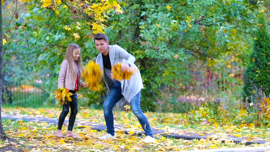 可爱的小女孩和快乐的父亲与母亲在户外秋季公园享受秋日视频