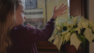 在悲伤的雨天后金发小女孩看着窗外玻璃上的水滴15秒视频