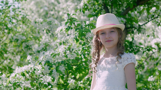 可爱的女孩站在树丛开花的附近笑着看镜头视频