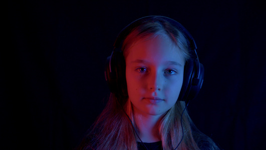 耳机里的可爱少女在黑暗中听音乐的视频
