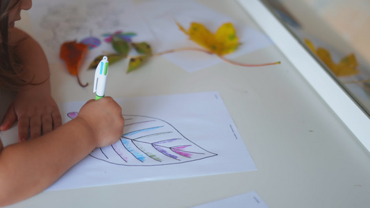 小女孩用笔在纸纸纸上涂着大叶子的彩色视频