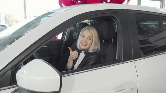 开心的女士坐在她的新车里举起大拇指视频