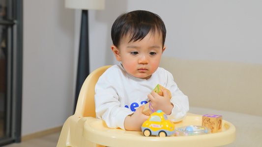 男宝宝坐在餐椅上玩玩具视频