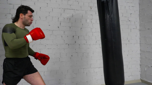 男子拳击手在手套训练中踢拳袋视频