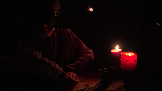 魔法师用羽毛笔和墨水在纸上写作蜡烛点燃了它视频