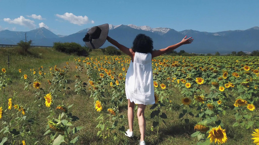 快乐的年轻女子在阳光明媚的夏日穿过向日葵田奔跑欢笑视频