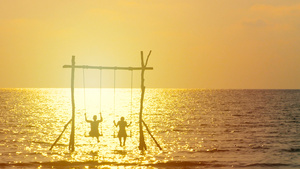 4K幸福的夫妇的剪影喜欢在日落时分在海面上荡秋千在20秒视频