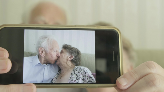 高龄夫妇对着镜头拿着智能手机视频