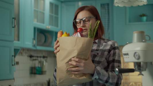 戴眼镜的年轻成年女性厌倦了拿着装着新鲜食物的纸袋开始视频