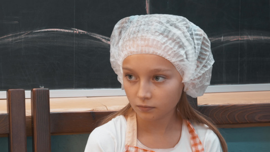 面对学校烹饪课上戴一次性帽子的少女肖像年轻女孩在烹饪视频
