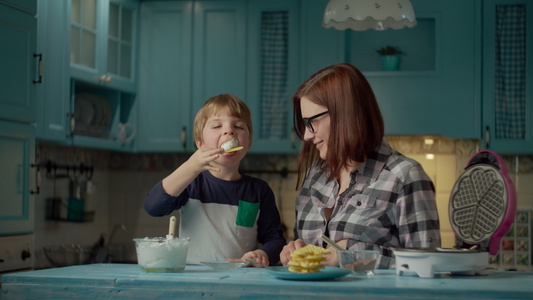 30多岁的年轻母亲帮助孩子把奶油和巧克力放在站在蓝色视频