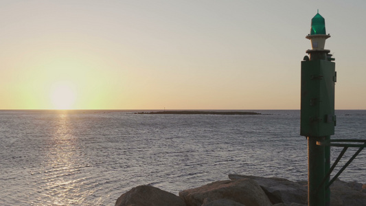 日出或日落时的大海全景镜头前景是港口的一座小灯塔日出视频