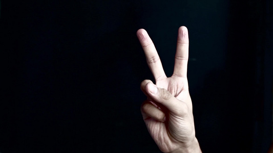 显示胜利或和平标志的手在黑色背景上视频