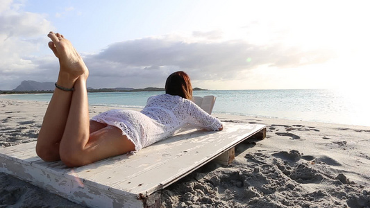 身后躺在海边躺着的年轻女子穿着白丝裙白内裤和长头发视频
