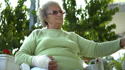 手受伤的年老老年妇女在户外坐在咖啡厅喝咖啡视频