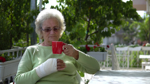 手受伤的老年妇女在户外喝咖啡22秒视频