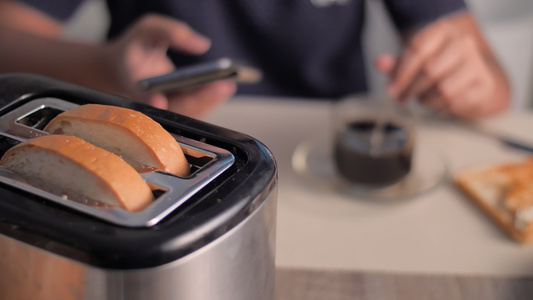 妇女使用智能手机烤面包片在厨房里为早餐煮咖啡视频
