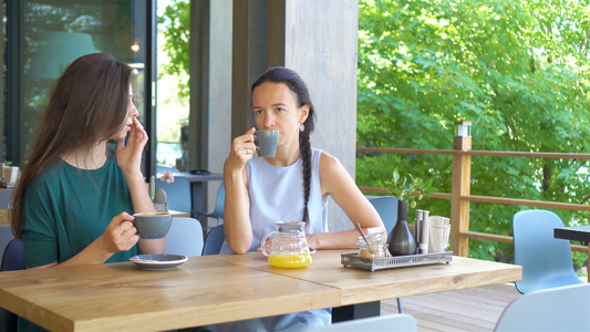 在咖啡馆用咖啡杯盛开着快乐微笑的青年妇女交流和友谊视频