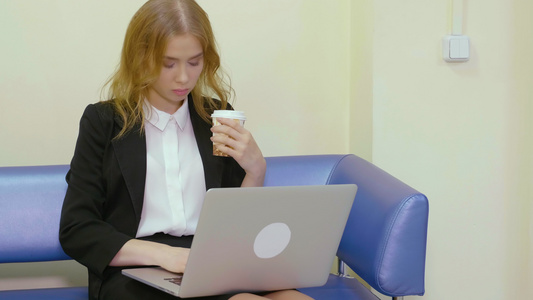 坐在沙发上用笔记本电脑工作的有咖啡的漂亮女商人视频