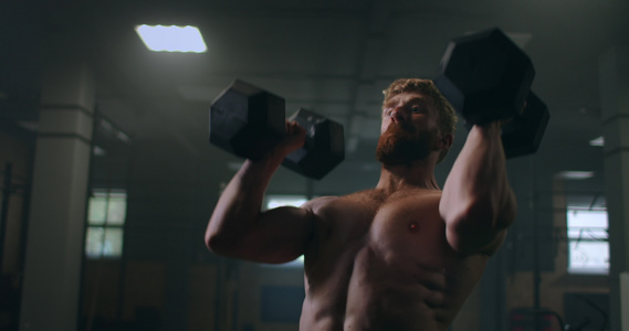 健身房里一个男人用哑铃砸头部的肖像训练耐力手臂和肩膀视频