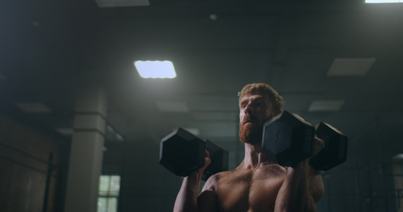 一个强大强健的运动员缓慢地推着哑铃站在健身房里视频