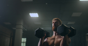 一个强大强健的运动员缓慢地推着哑铃站在健身房里20秒视频