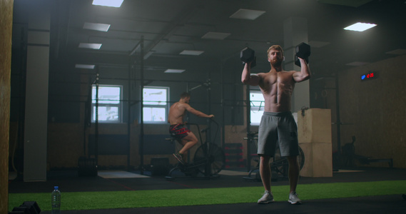 一个人在做繁重的锻炼后会把哑铃扔到健身房的地板上视频