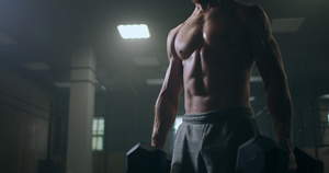 一个强壮的男人手里拿着哑铃在健身房做弯腰24秒视频