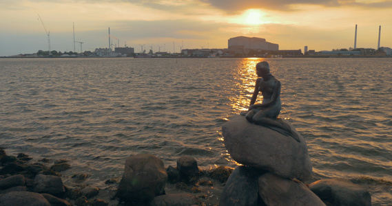 日落时在城市水边的美人鱼雕像视频