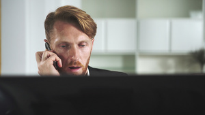 红头发男人坐在电脑前打电话20秒视频