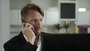 红头发男人坐在电脑前打电话19秒视频