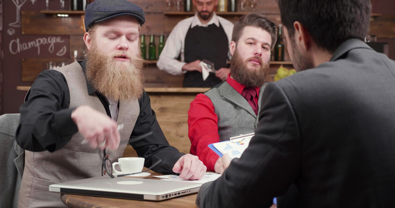 在古董酒吧与两个留胡子商务男性讨论视频