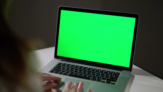 妇女工作或使用笔记本电脑使用绿色屏幕染色体显示视频