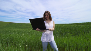 女孩独自站在绿色田地里拿着笔记本电脑8秒视频