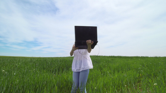 女孩独自在绿色田地使用笔记本电脑视频