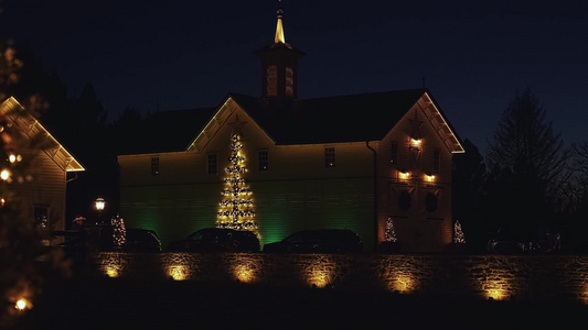 在恢复的古董谷仓举行圣诞节照明展览并配有树木和花圈视频