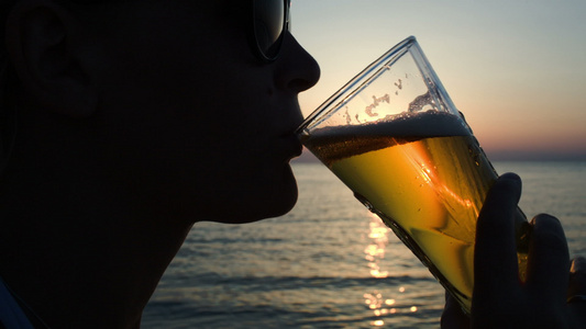 日落时在海滩上喝啤酒的女人视频