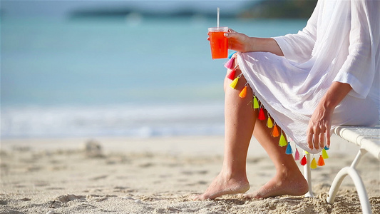 白沙滩上的年轻女子坐在阳光下喝着美味鸡尾酒视频