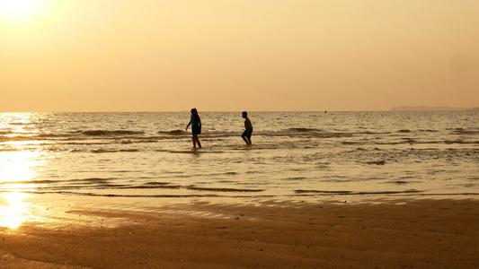 姐姐和弟弟在日落时分在海滩上奔跑和玩水的剪影美丽和视频