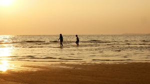 姐姐和弟弟在日落时分在海滩上奔跑和玩水的剪影美丽和11秒视频