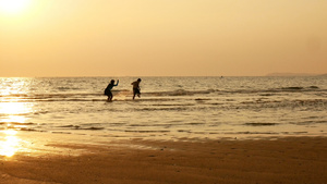 姐姐和弟弟在日落时分在海滩上奔跑和玩水的剪影12秒视频