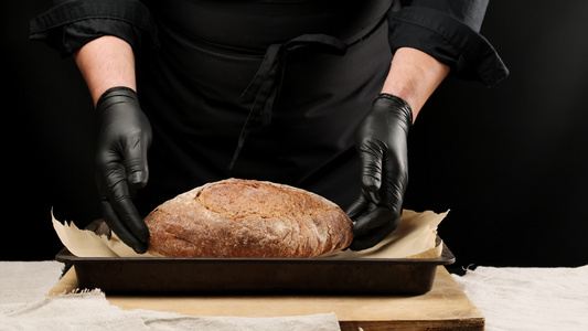 身穿黑色制服和黑色乳胶手套的男厨师将圆形烤面包放在视频