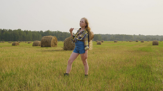穿着格斗衬衫和短牛仔裤的乡下女孩在田地上摆布在秋村视频