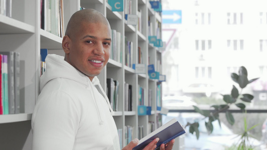 英俊的非洲男子在图书馆阅读时微笑着向相机微笑视频