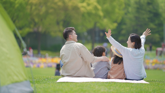 4k一家人在公园野餐坐在草坪上聊天背影视频